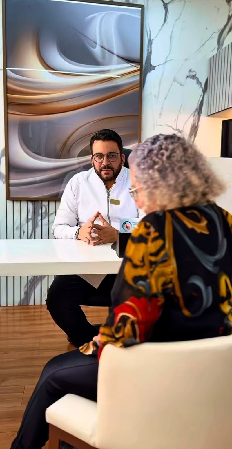 Dr. Kleber Rangel em consulta no consultório em Divinópolis, em postura de escuta atenta a uma paciente